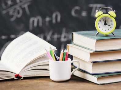 Bücher und Wecker auf einem Lehrerpult