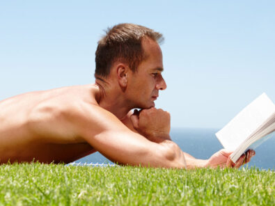 Mann liest im Sommer auf der Wiese ein Buch