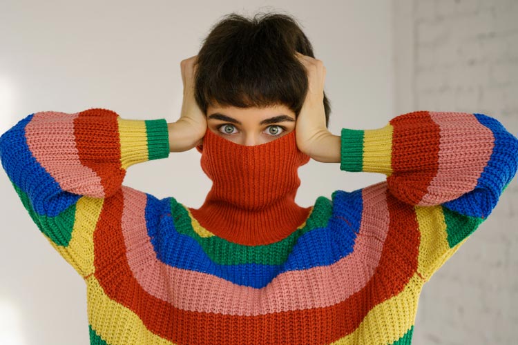 Frau im gestreiften Pulli versteckt sich hinter dem Rollkragen