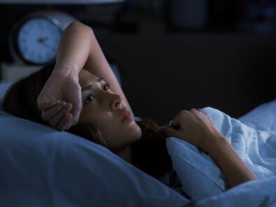 Frau liegt mit offenen Augen im Bett mitten in der Nacht