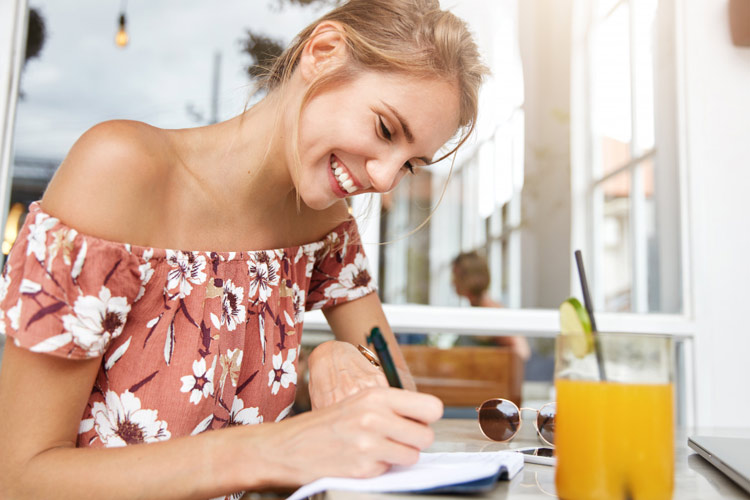 eine glückliche Frau schreibt in ihren Notizblock