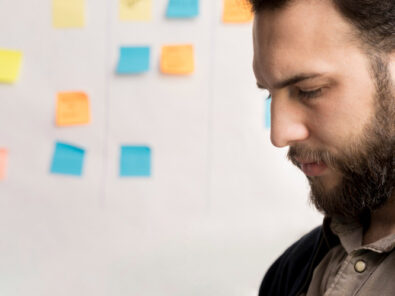 Mann denkt über seine To-dos nach mit Post-its im Hintergrund