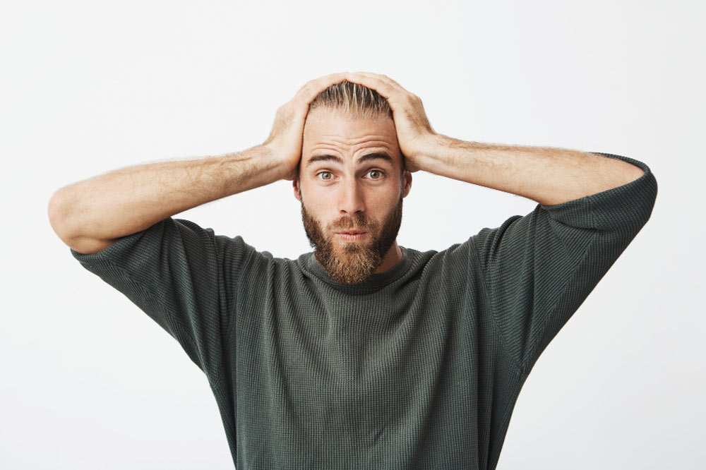 ein Mann hält sich die Hände überfordert über dem Kopf zusammen