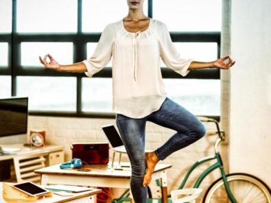 Frau steht in der Tree Pose neben dem Schreibtisch